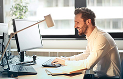 Strom und Gas Kombitarife | Lohnt sich ein Ansprechpartner? Mann sitzt am Schreibtisch mit Computer und Büro-Utensilien.