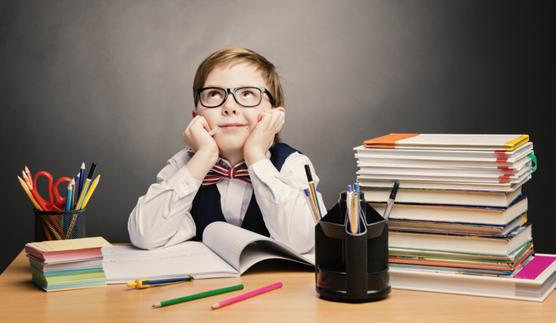 Tarifauswahlkriterien | Strom und Gas | Lexikon | cheapenergy24 Kleiner Junge mit Brille, Hemd, Weste und Fliege sitzt am Schreibtisch. Den Kopf in die Hände gestützt und nach oben schauend. Neben ihm ein Stapel Bücher und Büro-Utensilien.