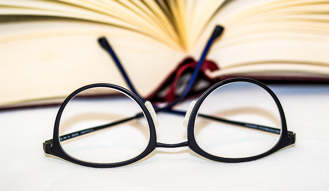 Stromanbieter und Gasanbieter kündigen Brille liegt auf dem Kopf vor einem aufgeschlagenen Buch