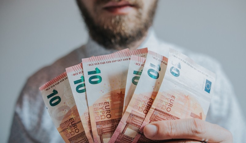 Stromanbieter verweigert Bonus – Verbraucherthemen Bärtiger Mann hält mehrere Zehn-Euro-Scheine in der Hand